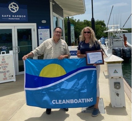A coordinator with an awarded clean marina staff, holding a clean marina flag and pledge.
