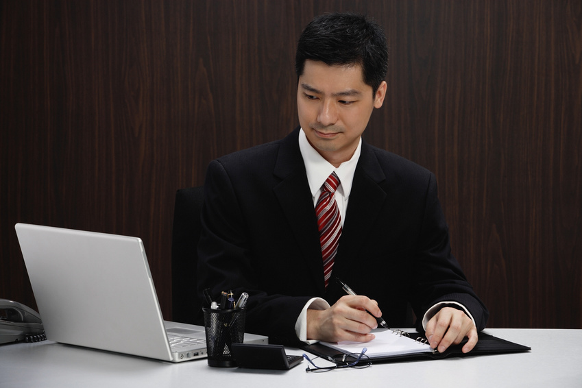 A businessman in a suit sits at his desk and computer