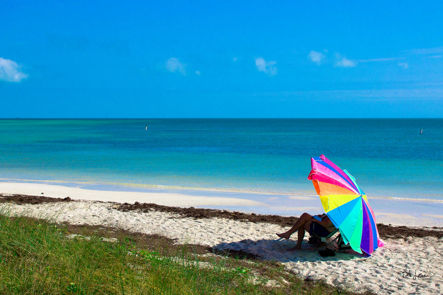 Person sitting under a beach umbrella at the coast of Bahia Honda State Park