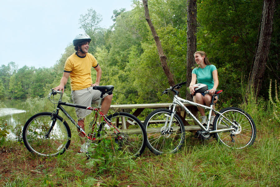 Aman and a woman sitting at a picnic table next to their bicycles on the Suwannee River Wilderness Trail