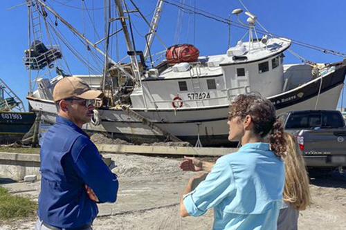 Secretary with residents and damaged shrimp boat