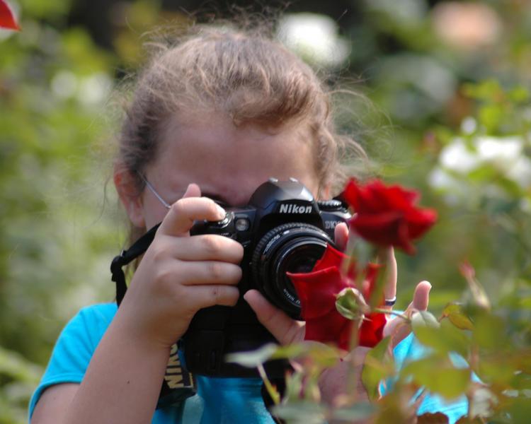 A young girl photographing a flower at Washington Oak Gardens State Park