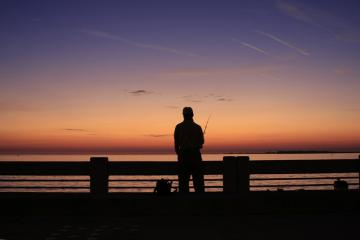 Silohouette of a man fishing from the pier at the Skyway Fishing Pier State Park